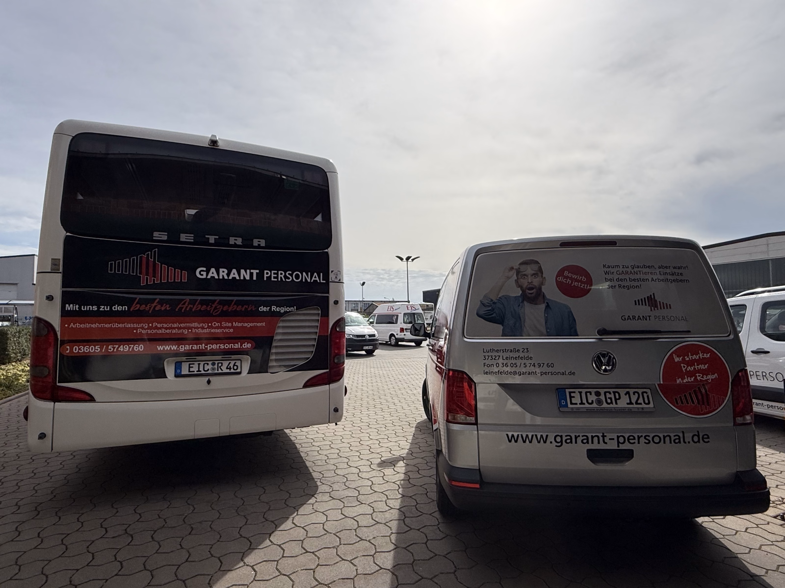 Heckansicht eines Werbebusses und eines Firmenwagens des Garant Personalservices