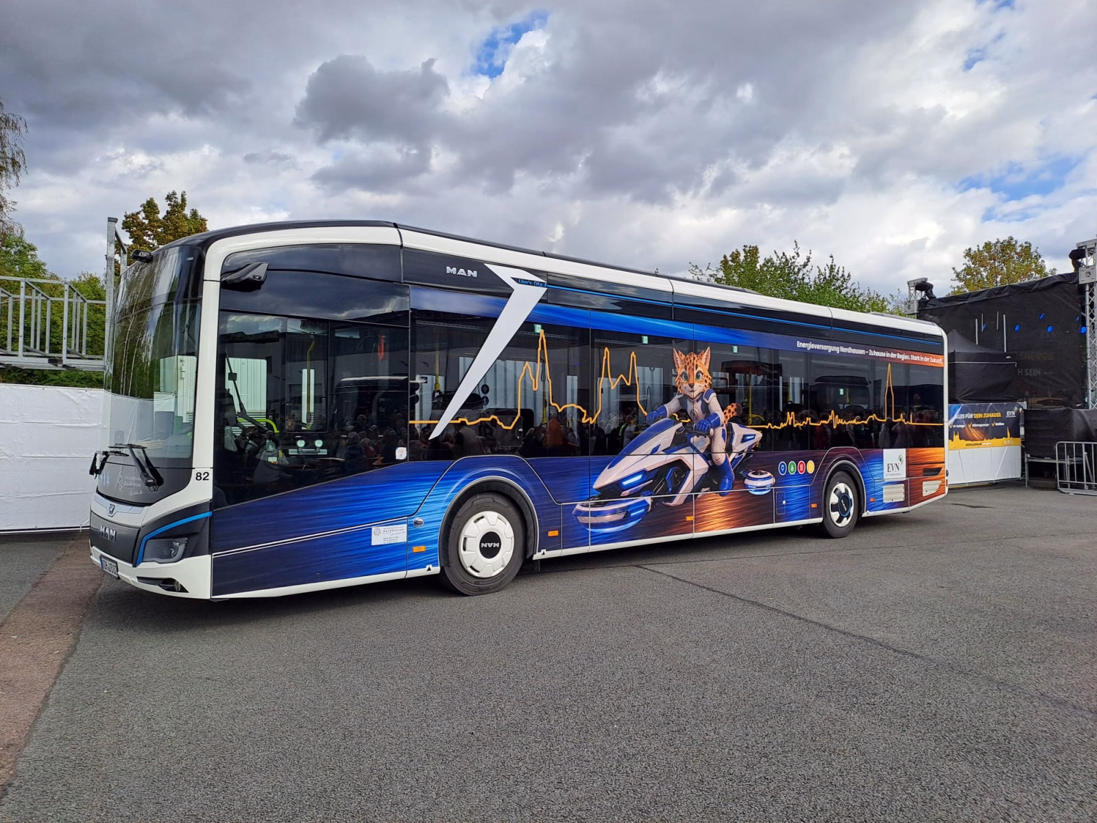 Seitenansicht eines blauen Stadtbusses mit einem großen Katzenmaskottchen