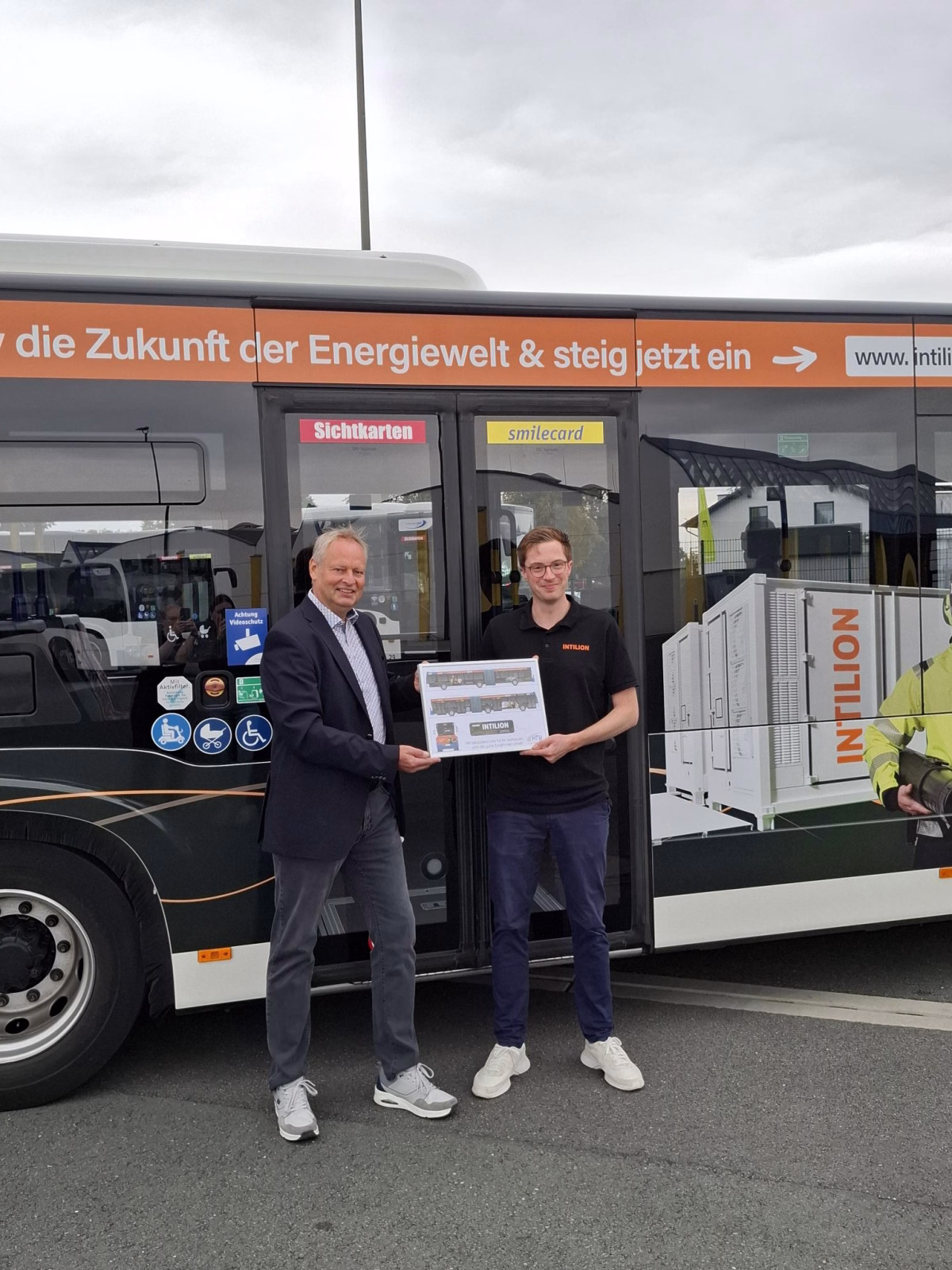 Zwei Männer stehen vor einem Gelenkbus mit Werbung von PaderSprinter