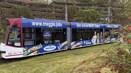 Seitenansicht einer blauen Straßenbahn der Meggle Bakery
