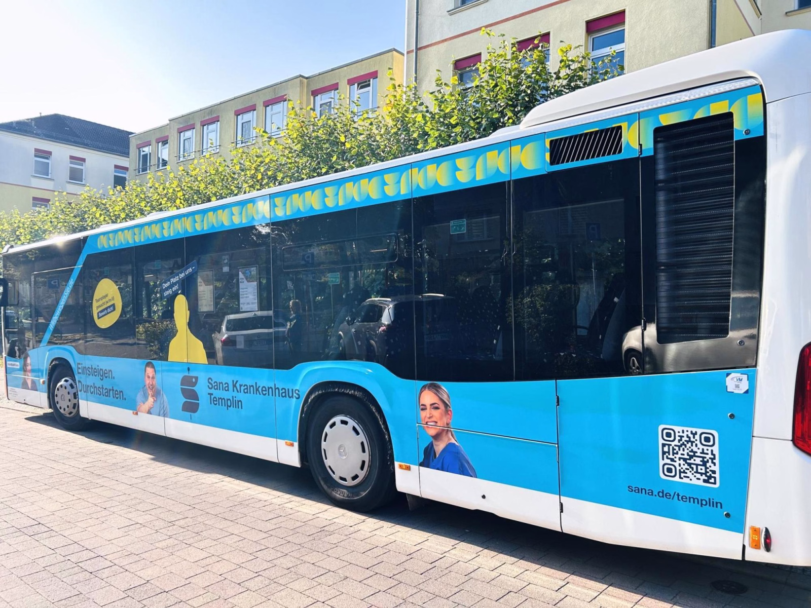 Außenansicht eines blauen Werbebusses mit Werbung des Sana Klinikums Templin
